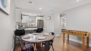 A dining area with a round table, chairs, and a foosball table.