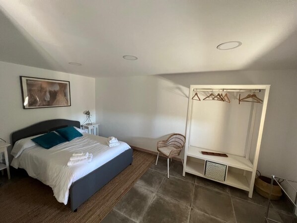 A bedroom with a bed, a chair, a wardrobe, and a painting on the wall.