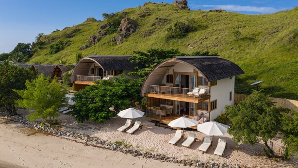 Propiedad en una ladera con dos cabañas de forma abovedada, cada una con balcón y terraza.
