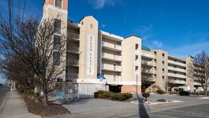 A multi-story hotel with a prominent "Ocean Castle" sign, outdoor parking, and a clear blue sky.