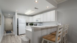 A modern kitchen with white cabinets, a microwave, and a built-in island with bar stools.