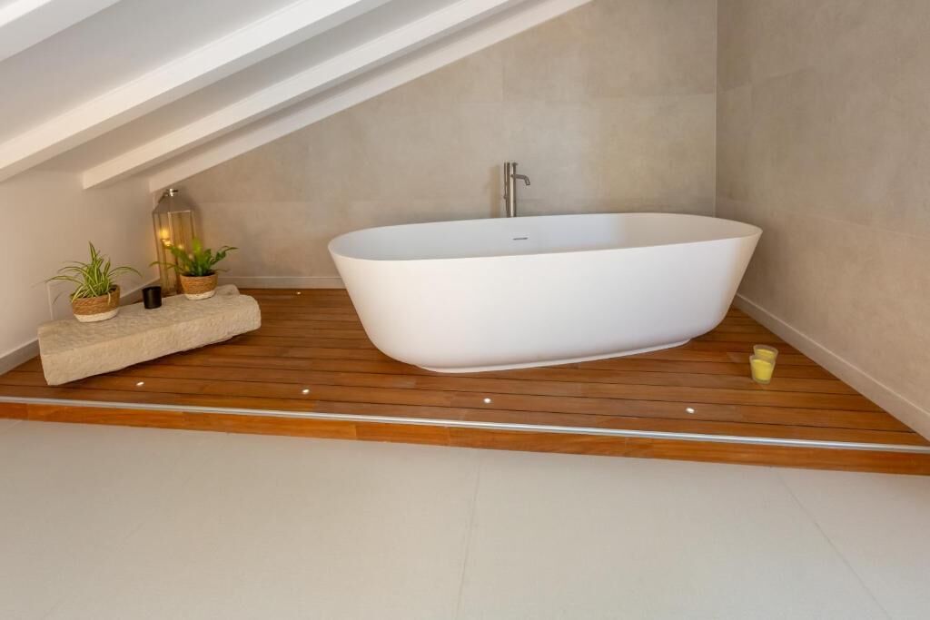 A modern bathroom with a freestanding bathtub, wooden flooring, and minimalist decor.