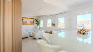 A modern living room with a white sofa set, a glass coffee table, and a view of the outside. - Traverse des Artistes (Cannes)