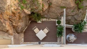 A rock-clad outdoor seating area with a wooden deck, a metal railing, and potted plants. - Traverse des Artistes (Cannes)