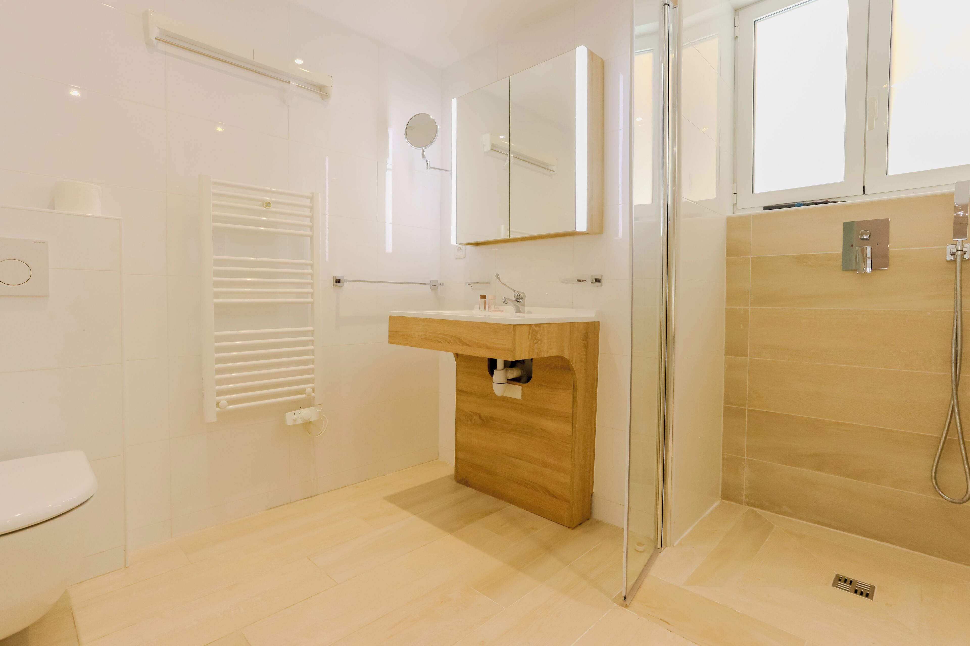 A modern bathroom with a wooden vanity, a glass shower enclosure, and a toilet.