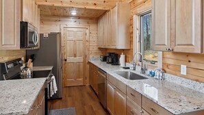 Eine kleine Küche mit Holzschränken, Granitarbeitsplatten und Edelstahlgeräten.