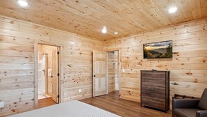 Ein Schlafzimmer mit Holzvertäfelung, einem Bett, einer Kommode und einem Bild an der Wand.