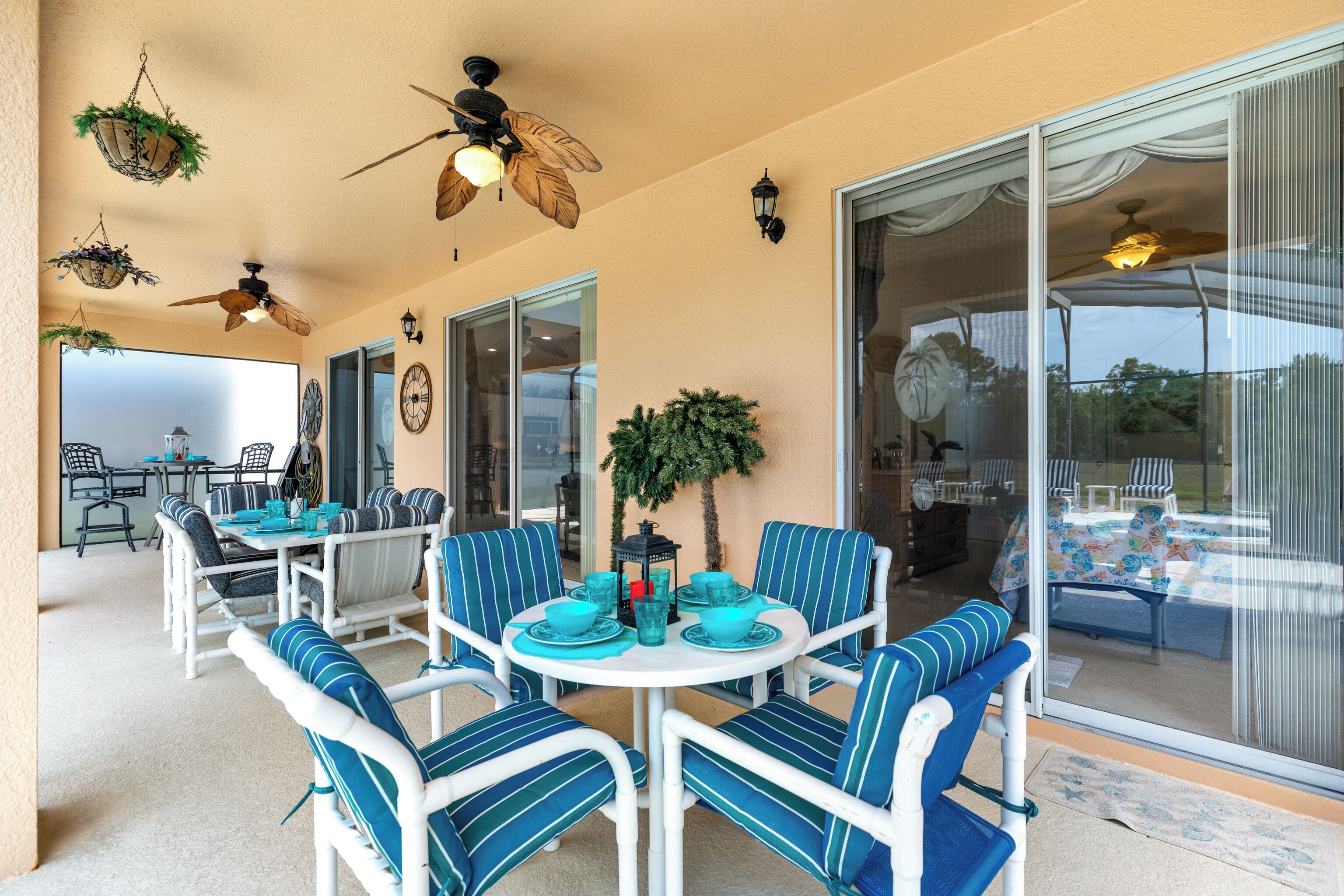 Une terrasse extérieure avec une table ronde et des chaises, des ventilateurs de plafond et une grande porte-fenêtre coulissante.
