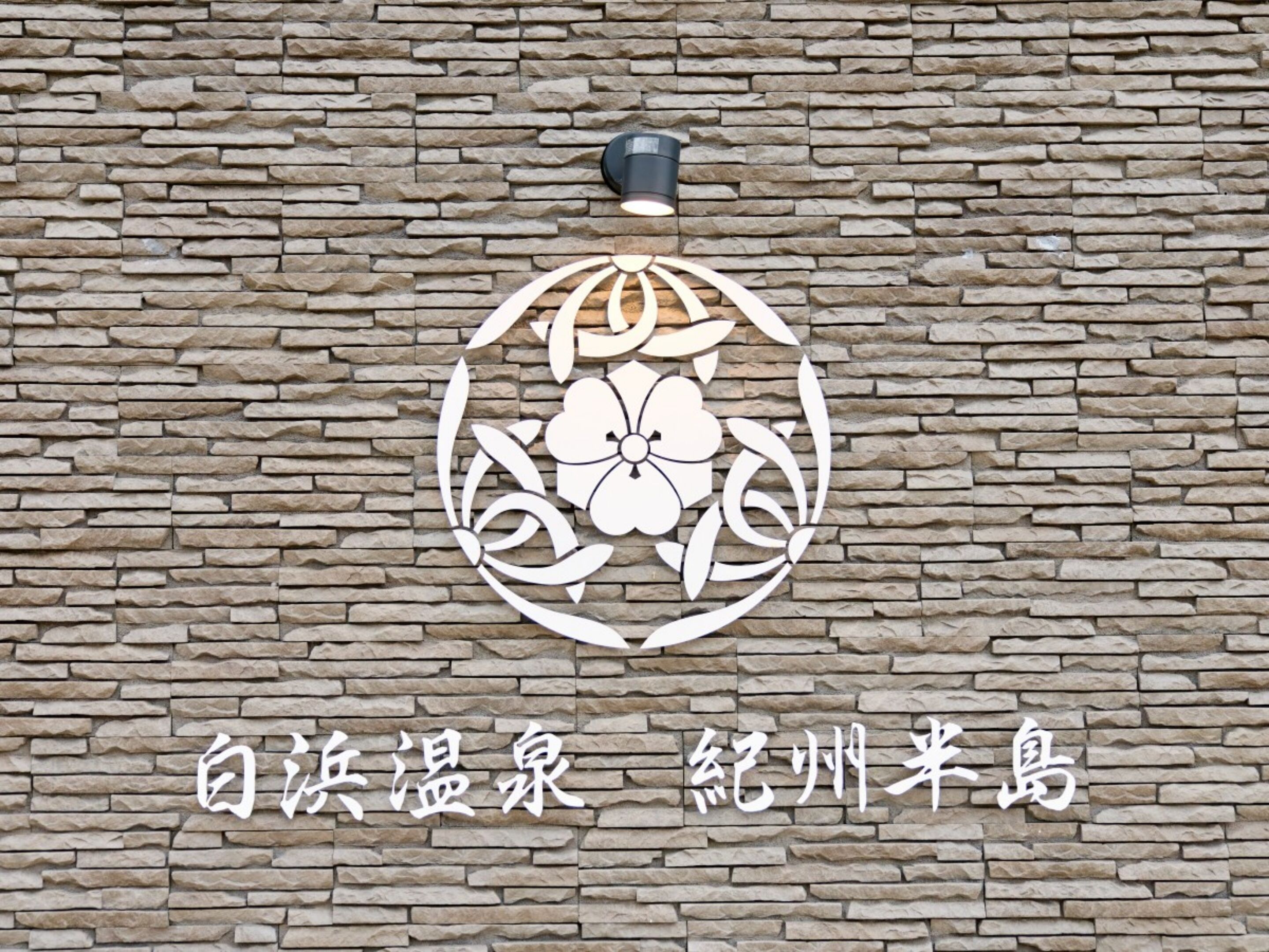 A stone wall with a decorative emblem and Chinese characters.