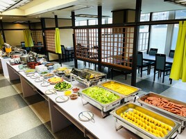 Un montaje tipo bufé con diferentes opciones de comida y un área de comedor con mesas y sillas.