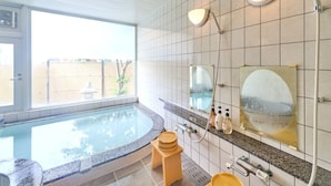 Un baño con una ventana grande, una bañera, ducha y un inodoro.