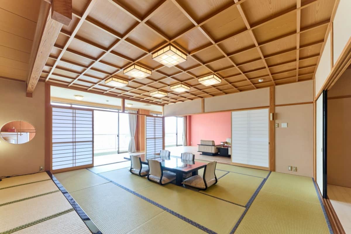 A traditional Japanese room with tatami flooring, a low ceiling with wooden beams, and sliding doors.