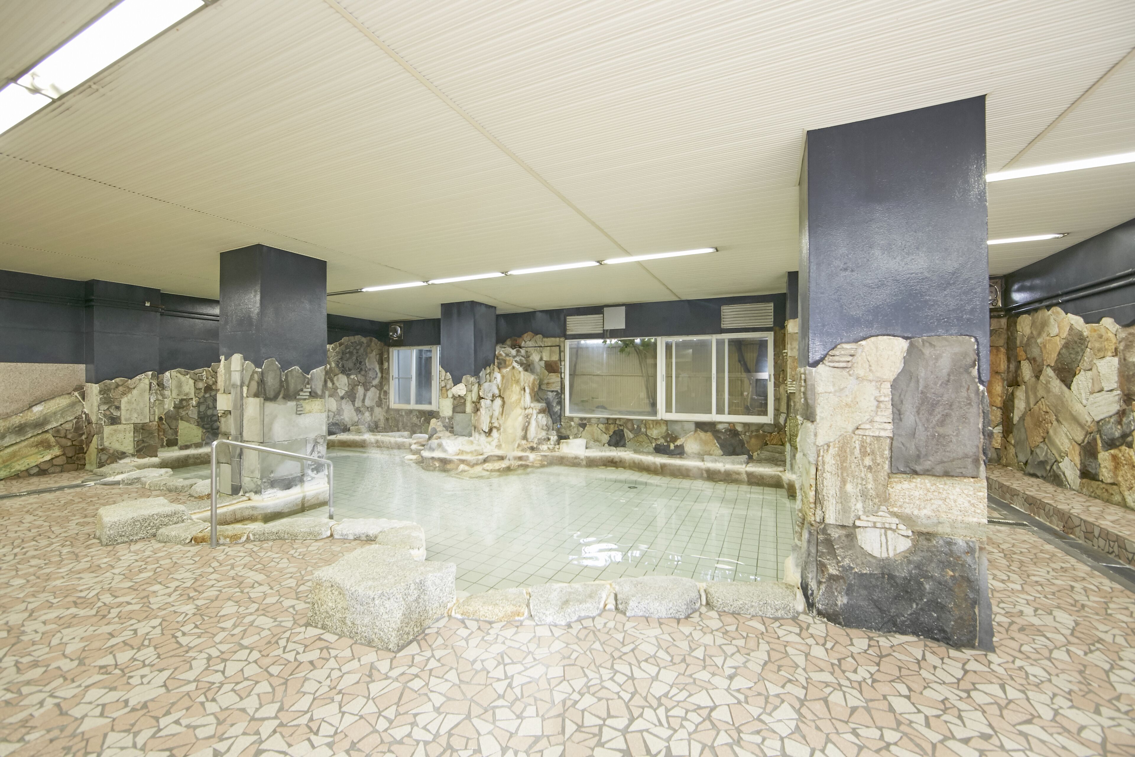 Una piscina interior con paredes de piedra y suelo de baldosas.