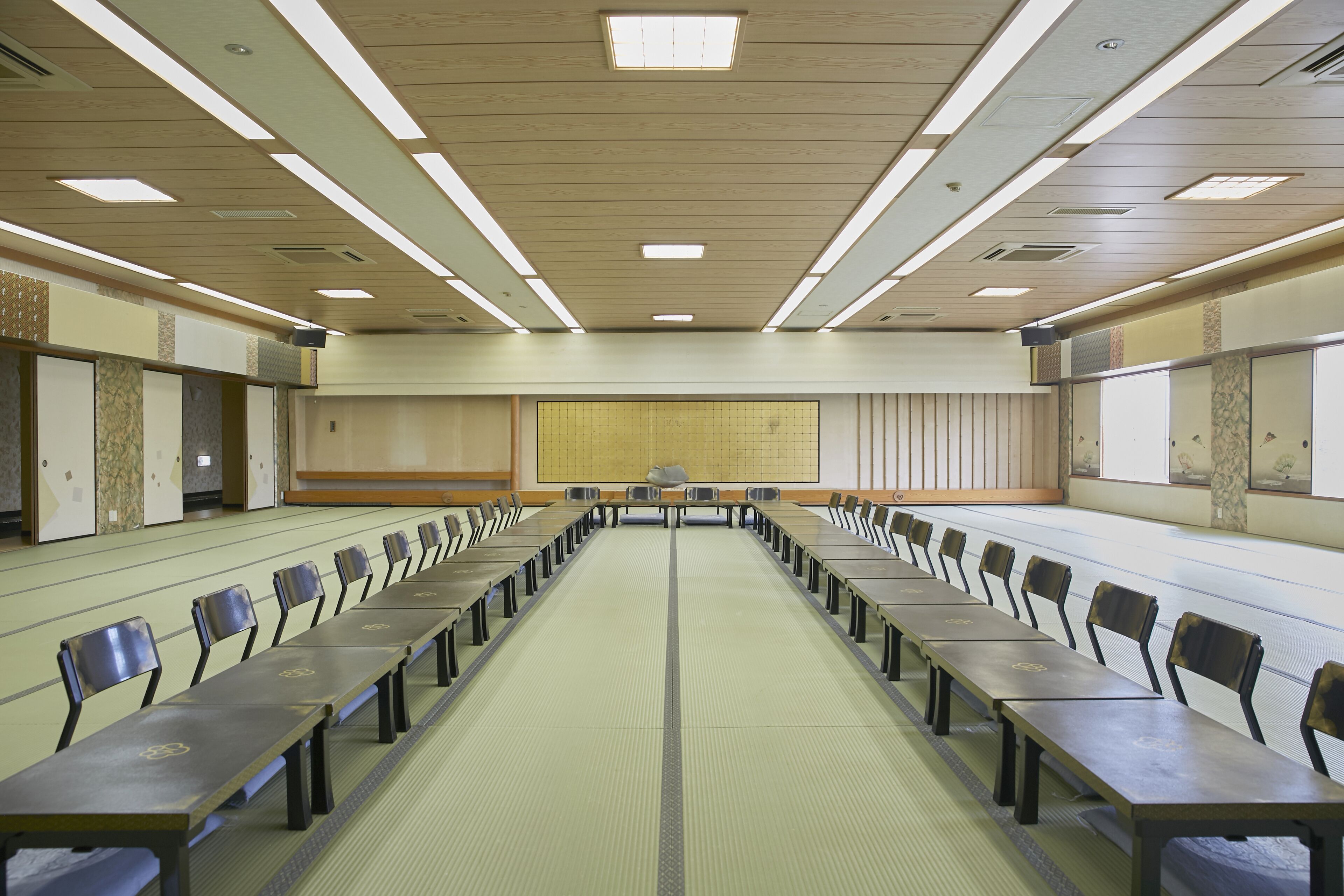 Une salle de conférence avec une longue table et des chaises, des murs recouverts de panneaux de bois et un grand écran à l’avant.