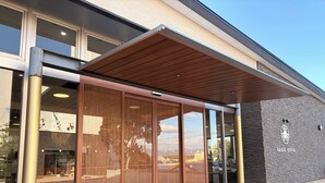 Una entrada de edificio moderna con una puerta de madera con listones, ventanas amplias y fachada de piedra.
