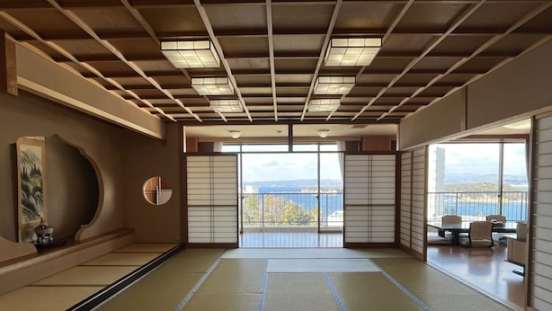 Una habitación tradicional japonesa con suelo de tatami, puertas correderas y vista al mar.