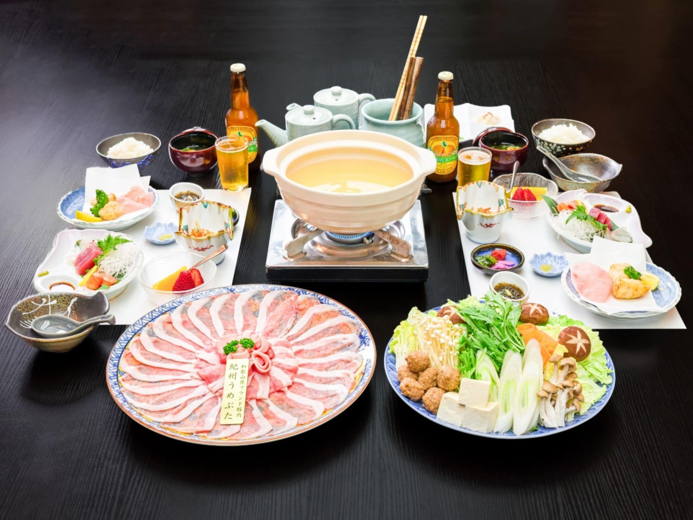 Variedad de platos japoneses, como sashimi, tofu y verduras, dispuestos sobre una mesa.