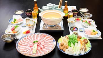 A variety of Japanese dishes, including sashimi, tofu, and vegetables, arranged on a table.