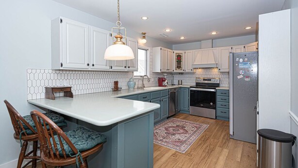 A modern kitchen with white cabinets, a central island, and a hanging light fixture. - Dog-Friendly house. Arctic Ave House: Sunny and bright beautiful 4 Bedroom 3 Full bathroom single home walking distance to the beach, Free WiFi, linens included. Remodel just in couple month. Great location, walk in to restaurants, coffee shop, Acme (Ocean City)