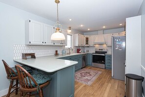 Een moderne keuken met witte kasten, een centraal eiland en een hanglamp.