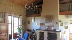 A spacious living room with a fireplace, a dining table, and comfortable seating. - Peaceful Retreat with Panoramic Views & Pool – Perfect for Families & Friends (Saint-Romain-de-Monpazier)