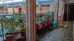 Un espacio al aire libre techado con plantas en macetas y una zona de juegos para niños.