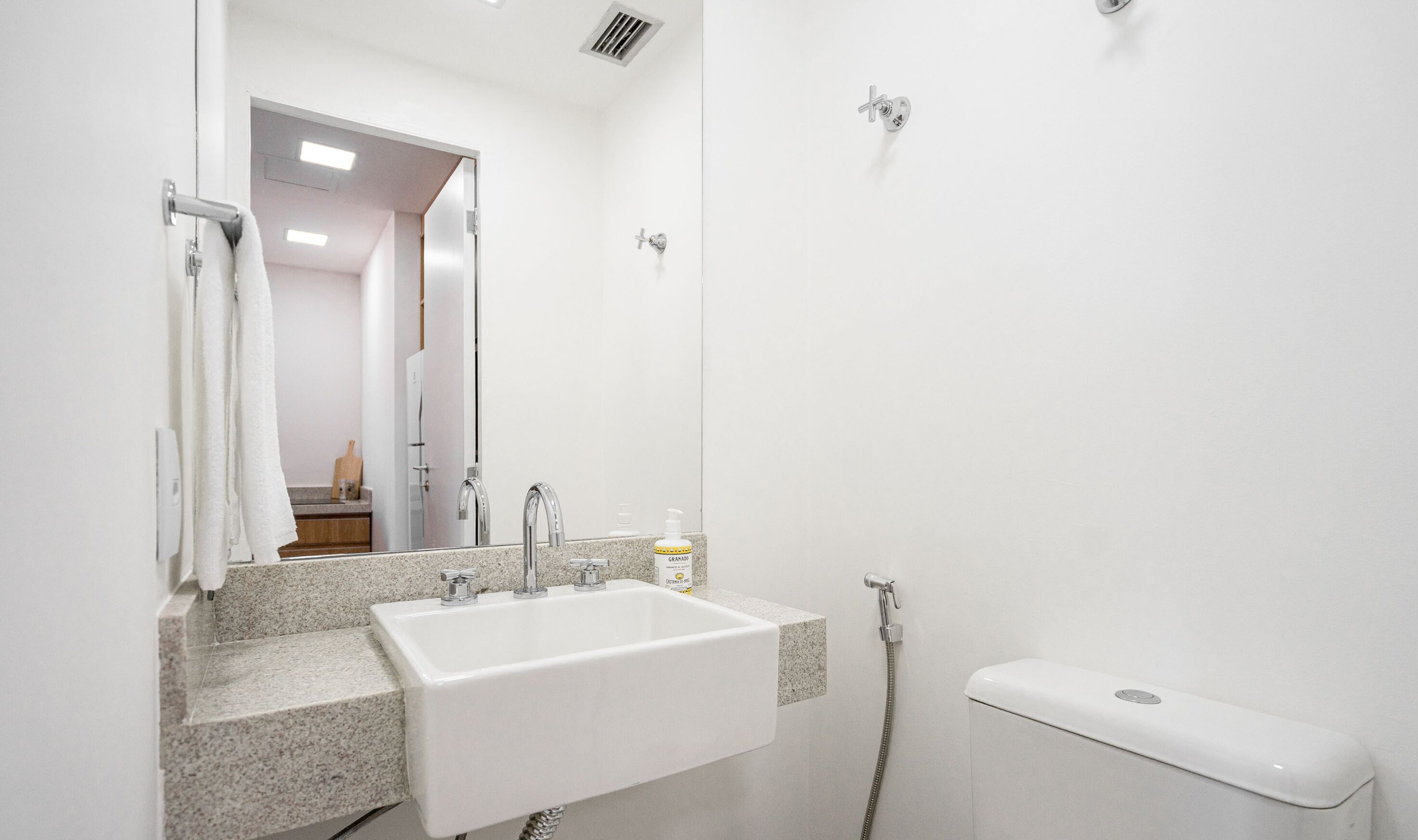 Une salle de bain moderne avec un lavabo blanc, deux robinets, un miroir et une douche.