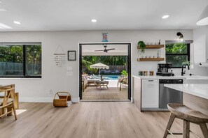 A modern kitchen with a view of a pool and outdoor seating area. - Coco Loco, tropical pool oasis near beach (Deerfield Beach)
