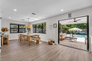 A modern interior with a dining area, a view of an outdoor pool, and a sign indicating no diving.