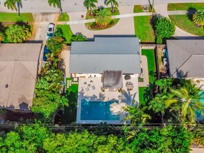 An aerial view of a residential property with a swimming pool, a covered patio, and surrounding greenery. - Coco Loco, tropical pool oasis near beach (Deerfield Beach)