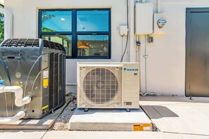 An outdoor air conditioning unit and a building with a window and a door. - Coco Loco, tropical pool oasis near beach (Deerfield Beach)