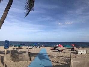 A beach with umbrellas, lounge chairs, and a clear view of the ocean.