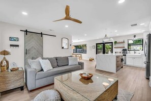 A modern living space with a sofa, coffee table, and kitchen area.