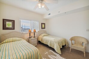 A bedroom with two beds, a nightstand, a chair, and a ceiling fan. - XPLORIE ACTIVITIES & LINENS INCLUDED*! Great 3BR Condo Just a Short Walk to the Beach, Dining & Activities! (Ocean City)