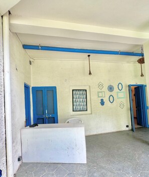 A room with a white reception desk, blue doors, and a tiled floor. - Mykonos Villa (Varanasi)