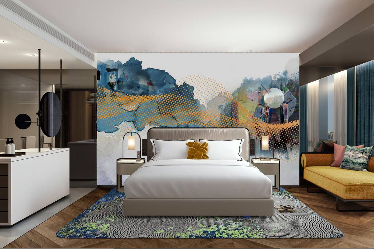 A modern bedroom with a large bed, bedside tables, a sofa, and a wall art piece.