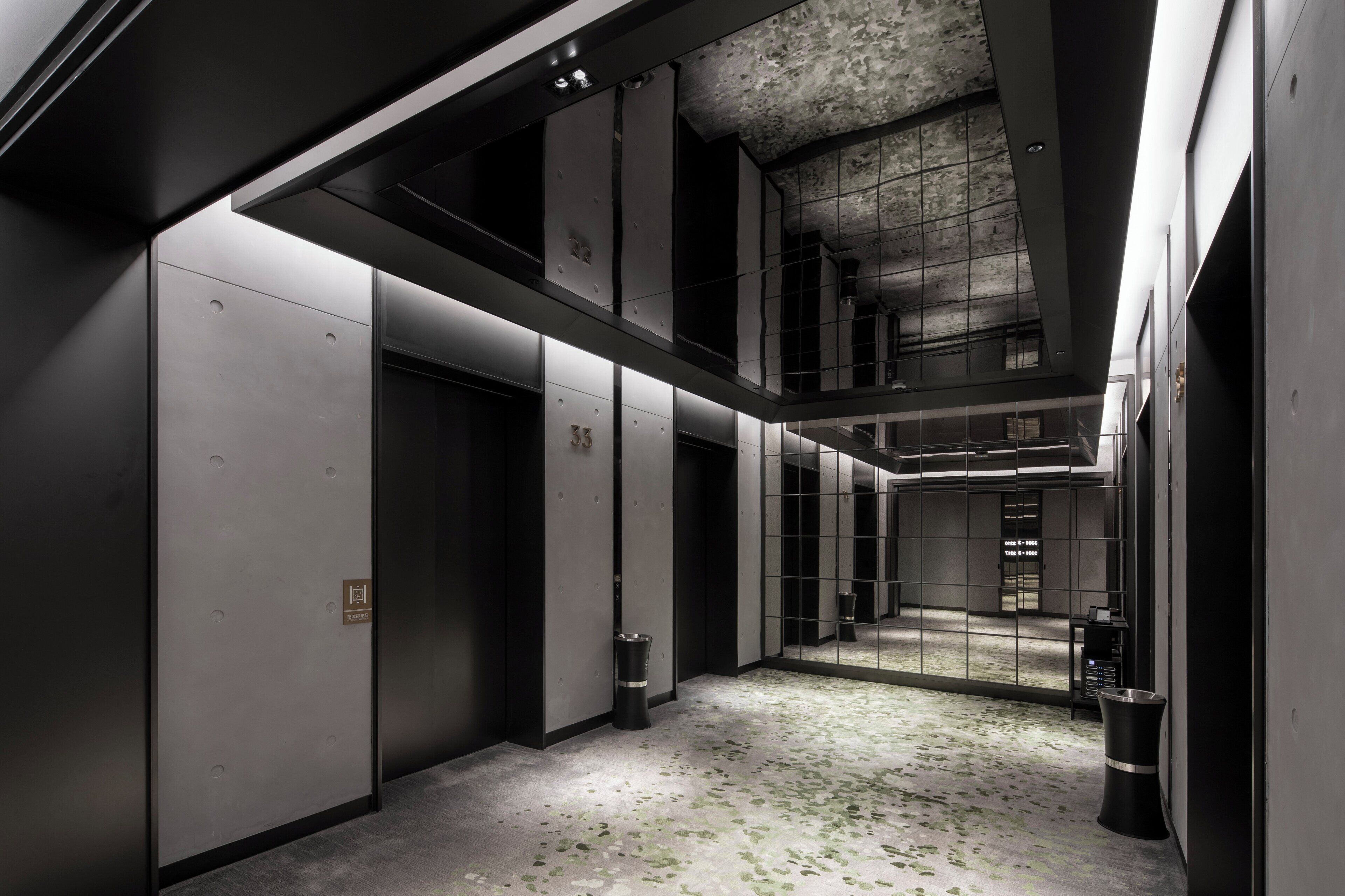 A modern interior with a high ceiling, reflective surfaces, and a minimalist design.