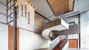 A modern interior with a spiral staircase, a wooden ceiling, and a wall with vertical text.
