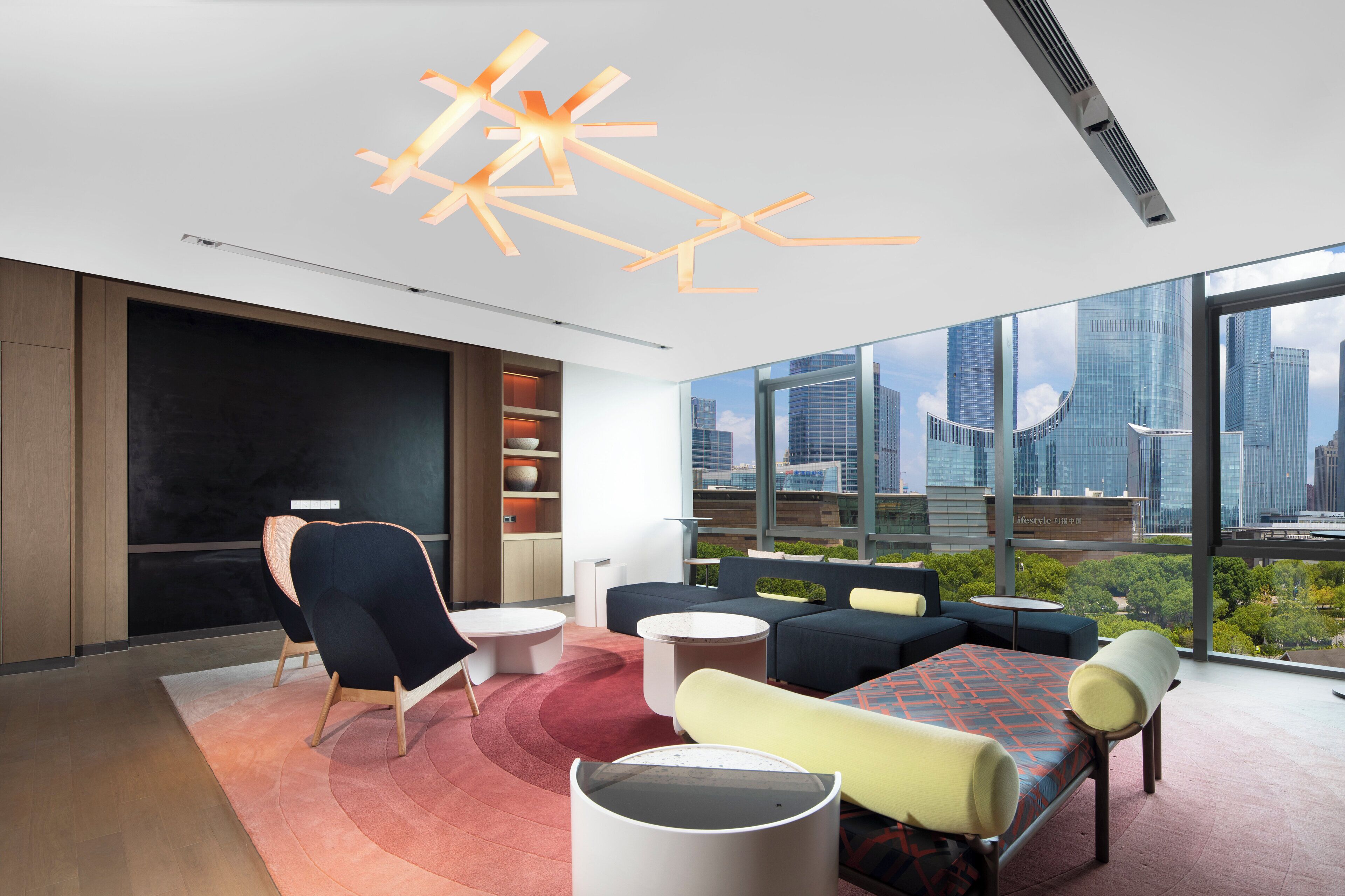 A modern hotel room with a city view, a large window, a round table, and a sofa.