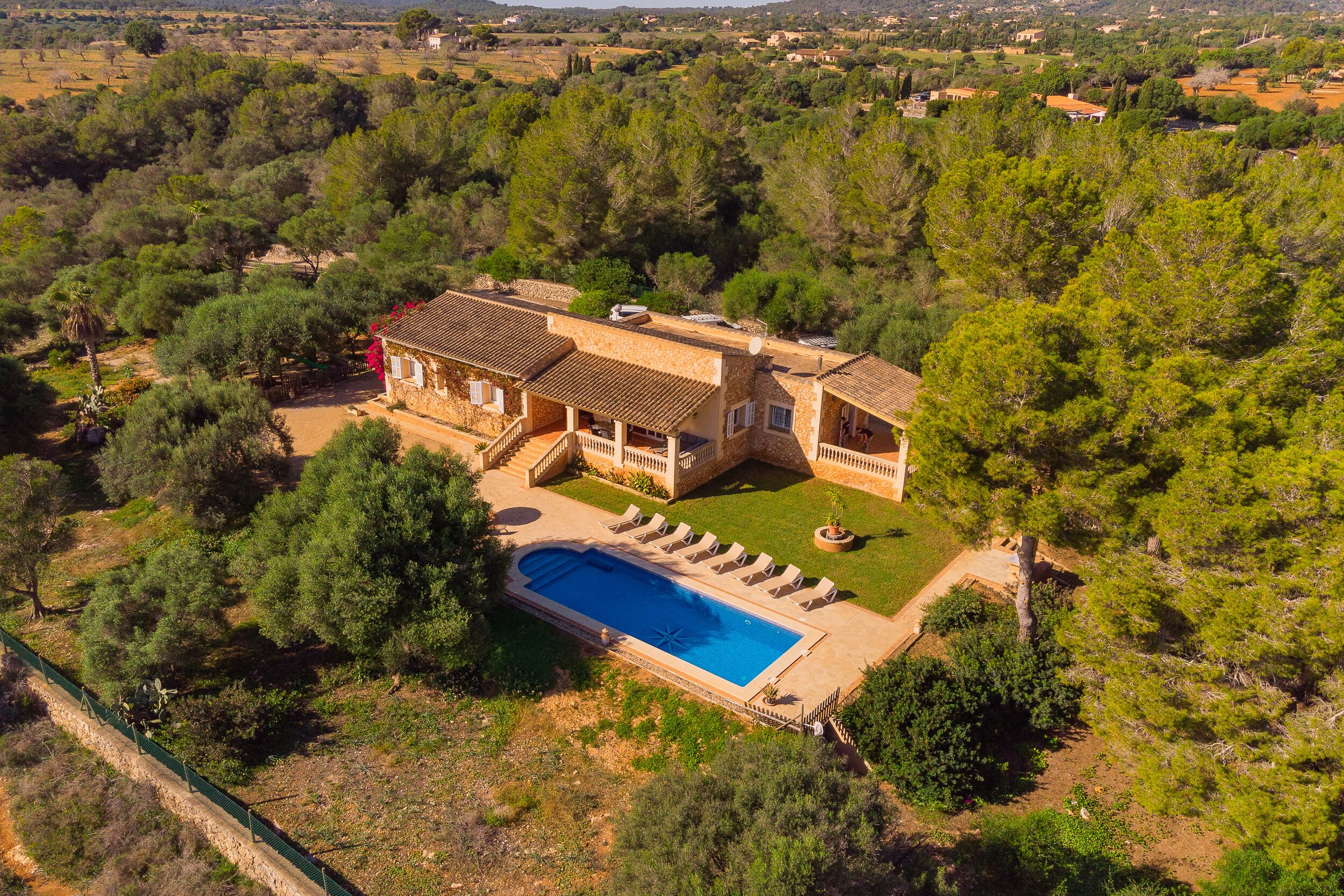 Une grande maison avec une piscine, entourée d’arbres.