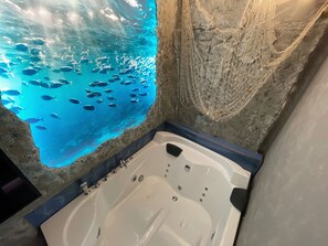 Et badekar med udsigt til et stort akvarium fyldt med fisk.
