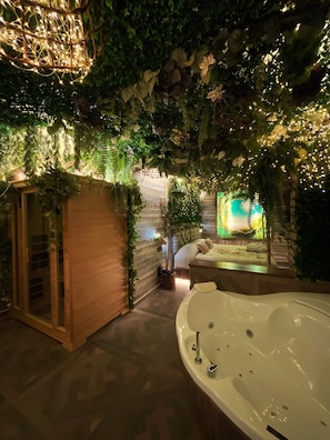 A spa area with a large bathtub, wooden sauna, and a wall decorated with plants and lights. - Suite Dreams Hotel Montecatini (Montecatini Terme)