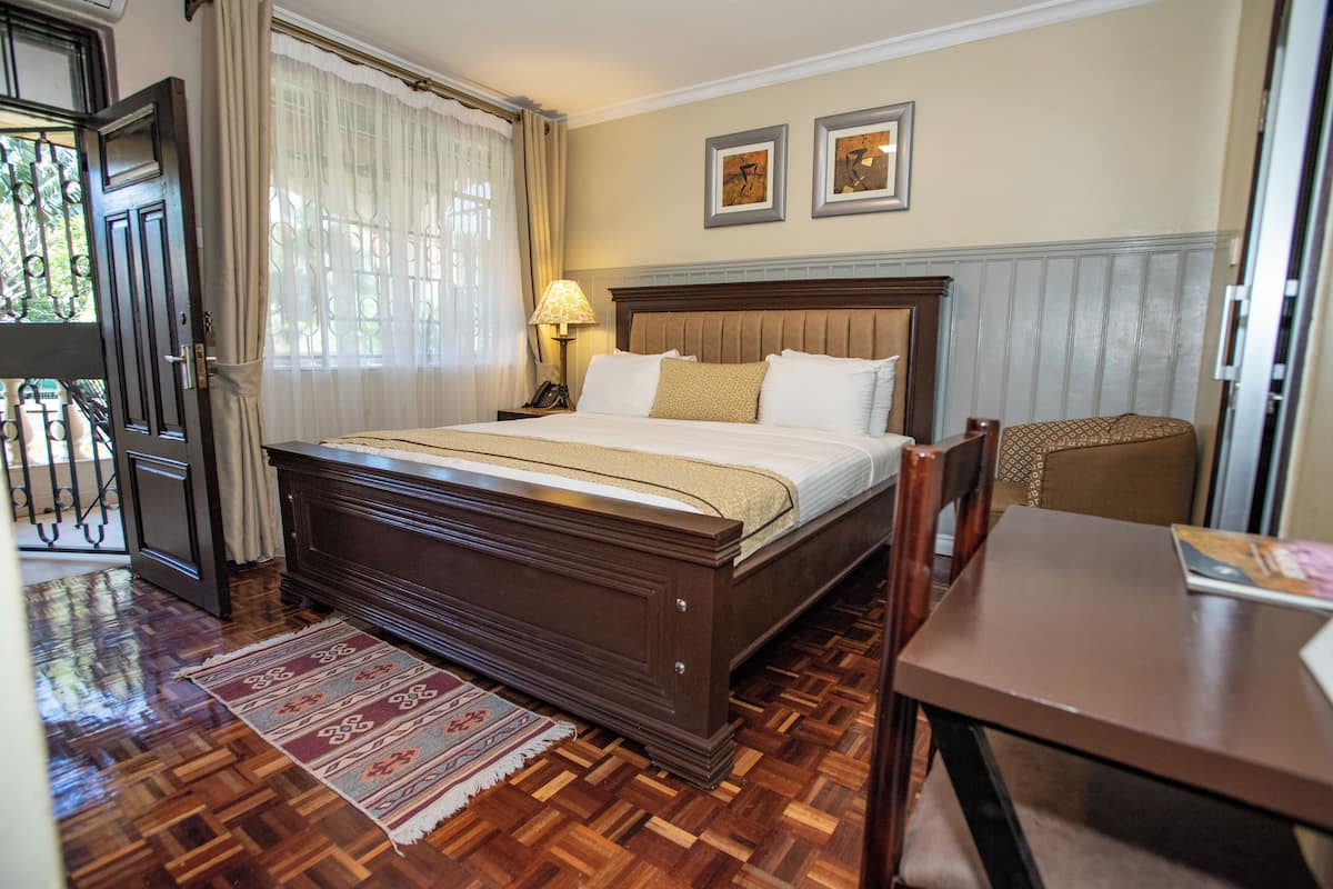 A neatly arranged hotel room with a large bed, a wooden table, and a chair.