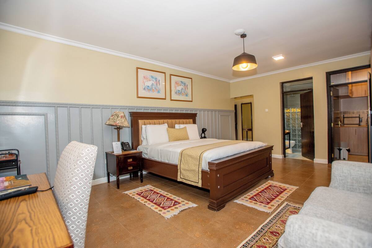 A bedroom with a wooden bed, two bedside tables, a nightstand, patterned rugs, and framed artwork on the wall.