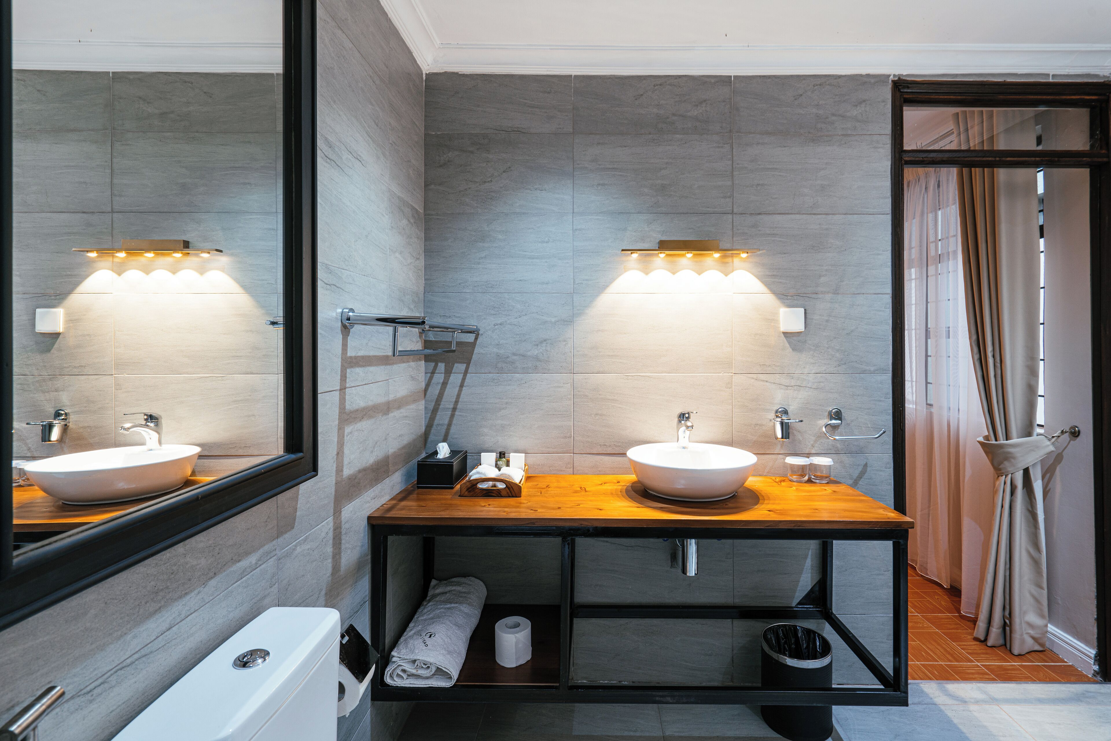 A modern bathroom with two sinks, a mirror, and a wooden vanity.