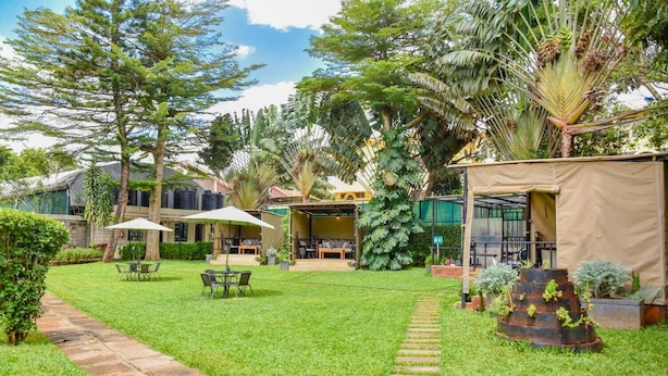 A well-maintained garden with a patio area, outdoor seating, and a variety of tropical plants. - Cozy Stead Hotel - Garden House, Gigiri (Nairobi)