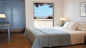 A bedroom with a bed, two bedside tables, a desk, and a door.