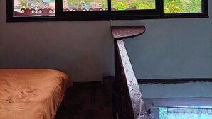 Ein Zimmer mit einem Bett, einem Fenster mit Blick auf eine hügelige Landschaft und einer Holztreppe.