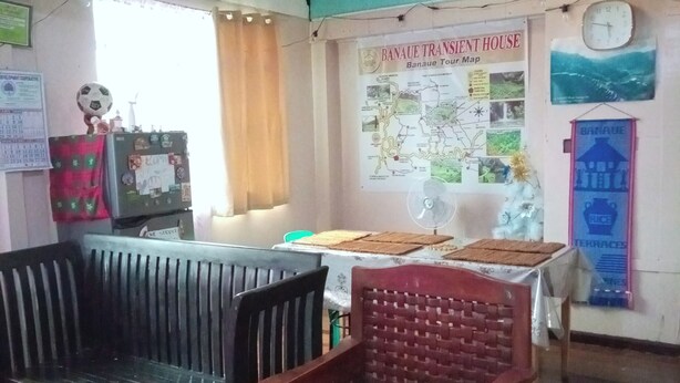 Una habitación con un banco de madera, una mesa con un mapa y un reloj en la pared.