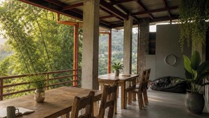 Una mesa de madera con sillas, una planta en maceta y vistas al verdor.